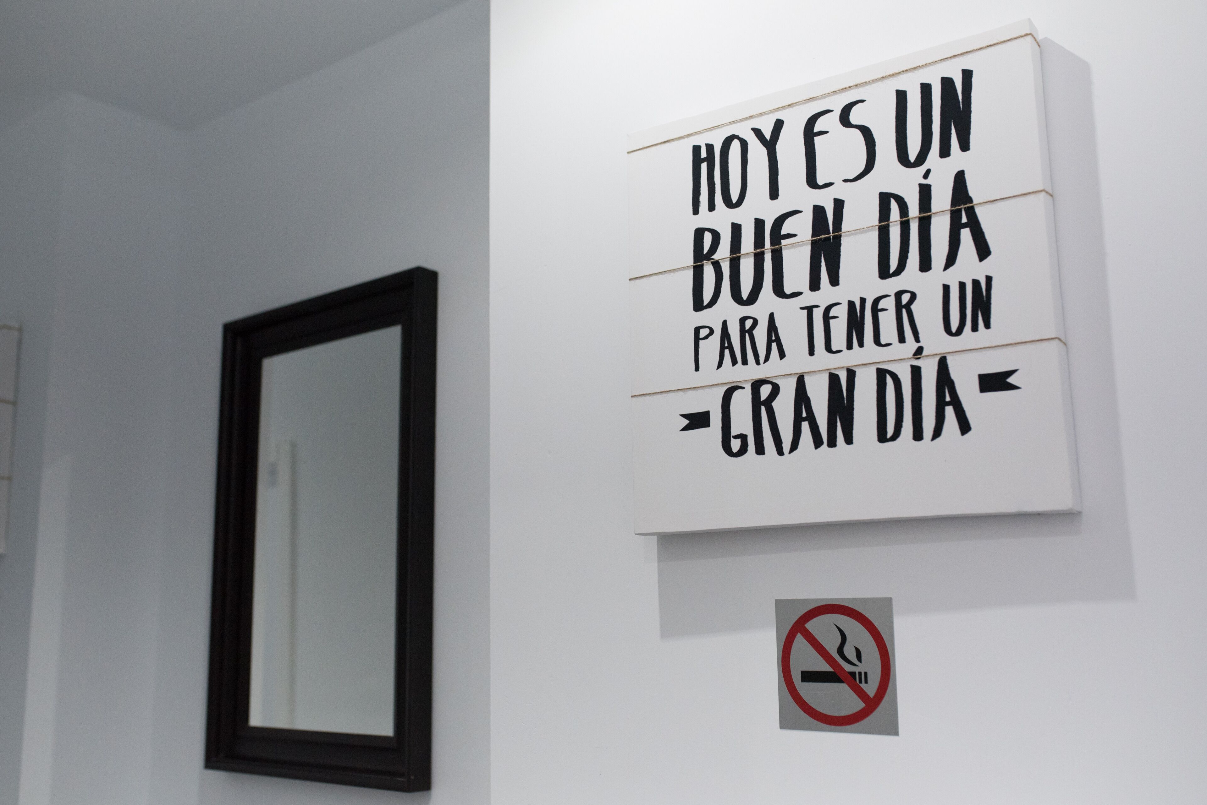 A wall with a motivational quote in Spanish and a no-smoking sign.