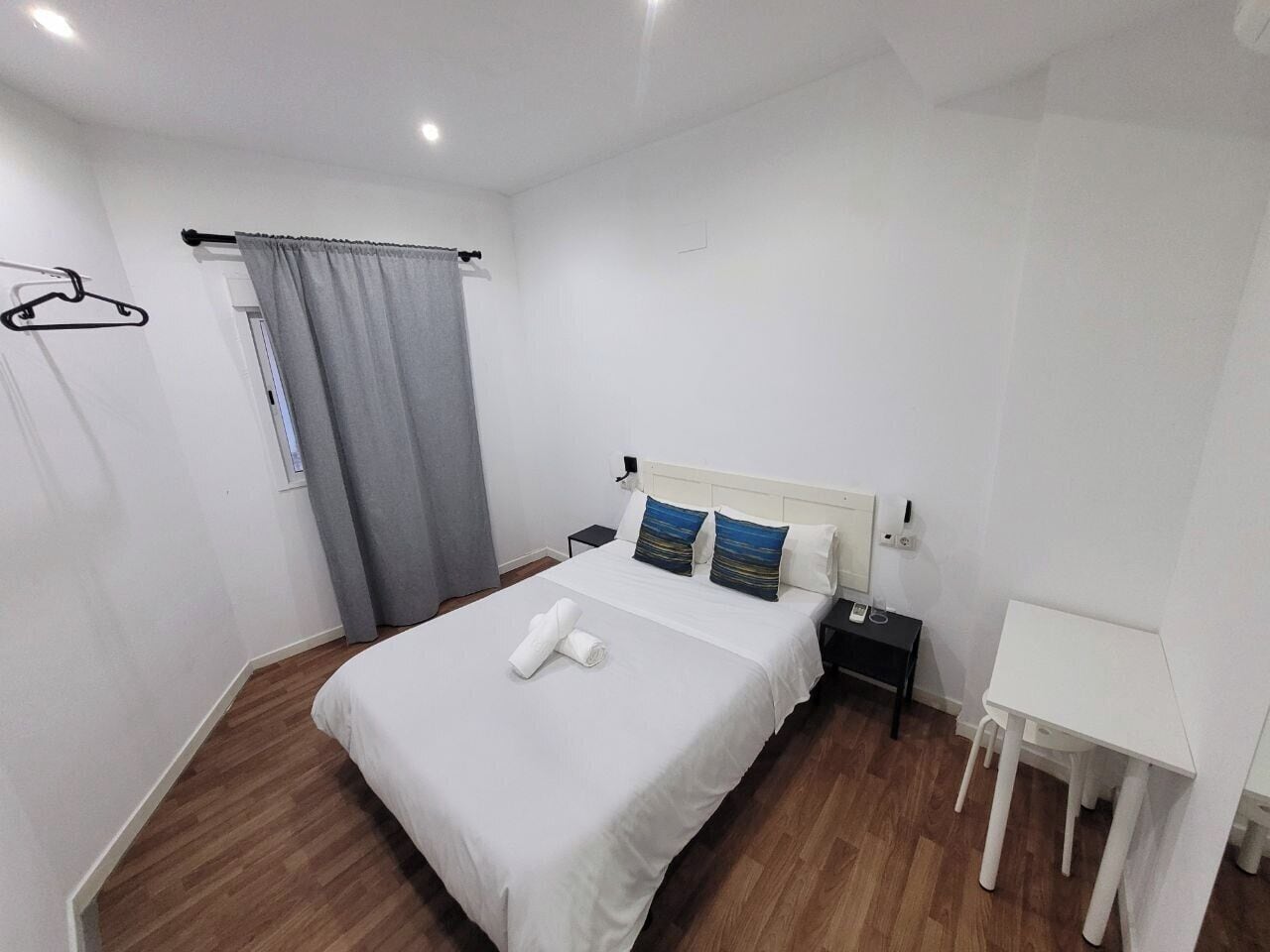 Een keurig opgemaakt slaapkamer met een bed, nachtkastje en een klein bureau.