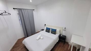 A neatly arranged bedroom with a bed, bedside table, and a small desk.