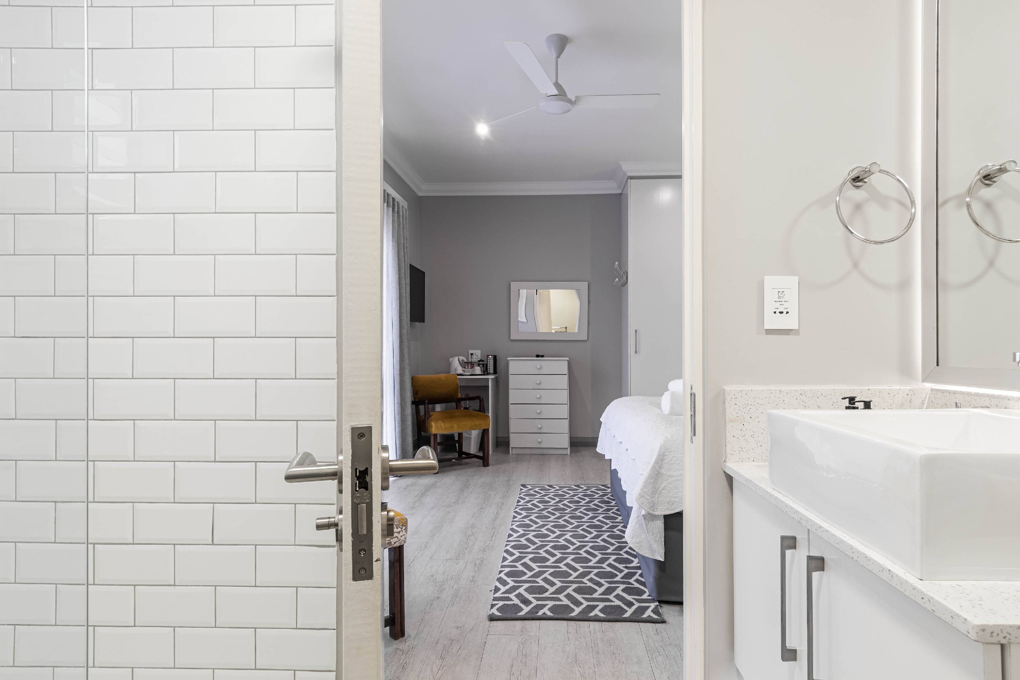 Un baño moderno con lavamanos, espejo y ventilador de techo.