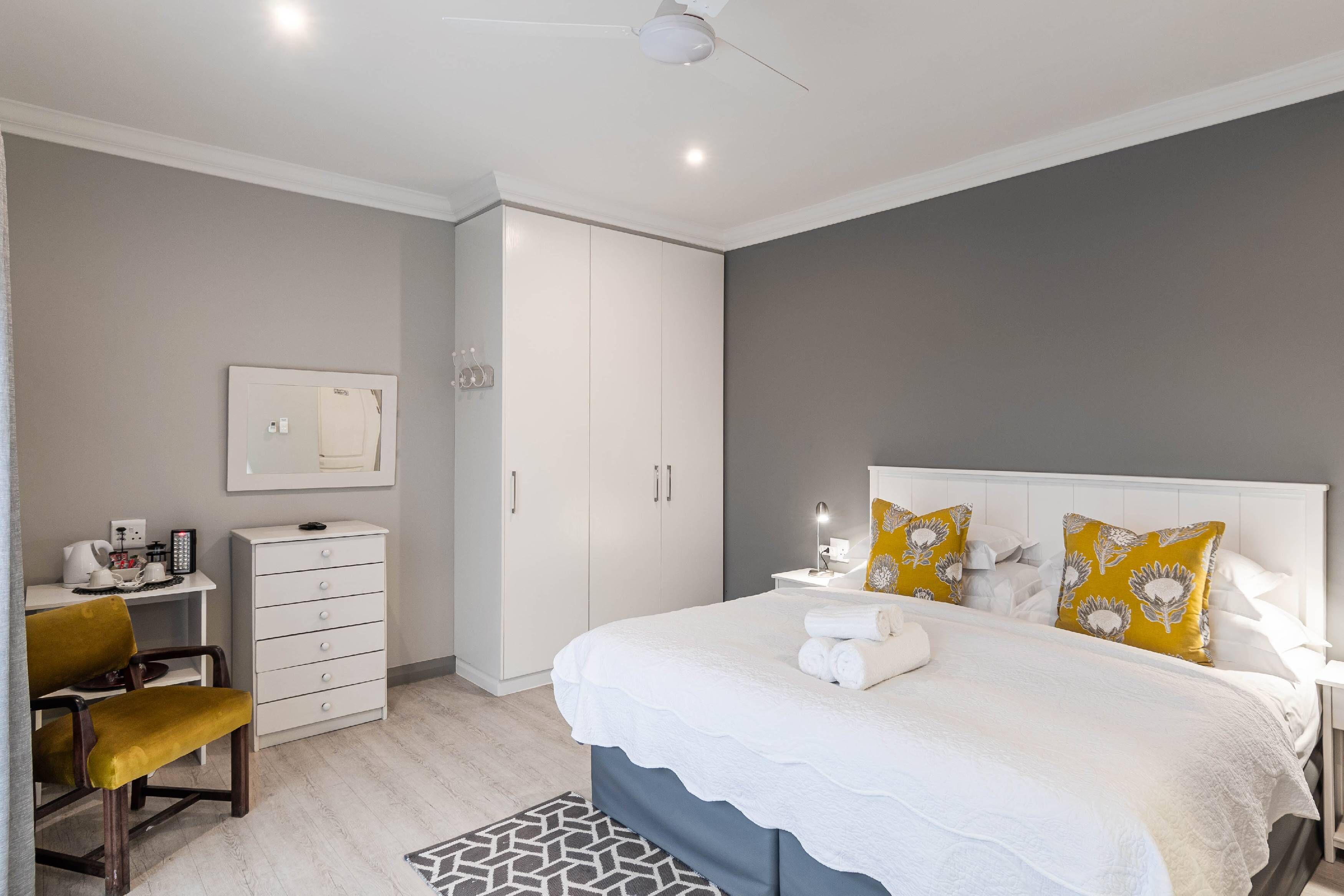 A bedroom with a bed, a desk, a chair, and a wardrobe.