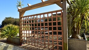 A wooden gate with a grid design, surrounded by potted plants and a clear sky. - Buttercup Cottage (Rye)
