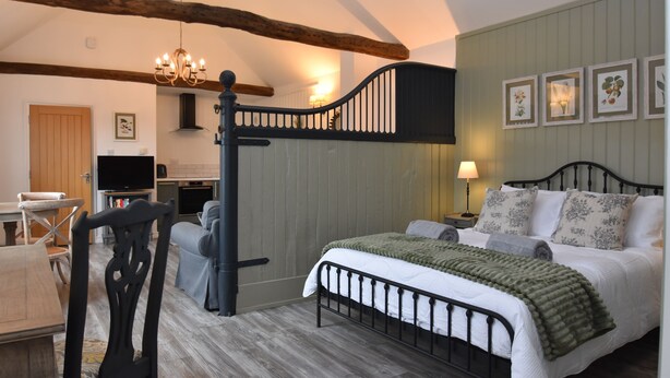 A bedroom with a bed, a desk, and a television. - Buttercup Cottage (Rye)