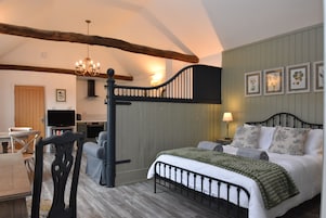 Quarto com cama, escrivaninha e televisão.