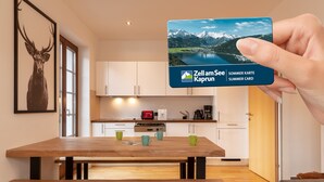 Eine moderne Küche mit Holzausstattung, einem Esstisch mit grünen Tassen und einem Bild eines Rehs an der Wand.