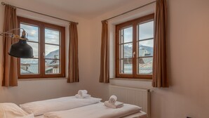 Ein Zimmer mit zwei Betten, einem Heizkörper und einem mit Vorhängen versehenen Fenster.