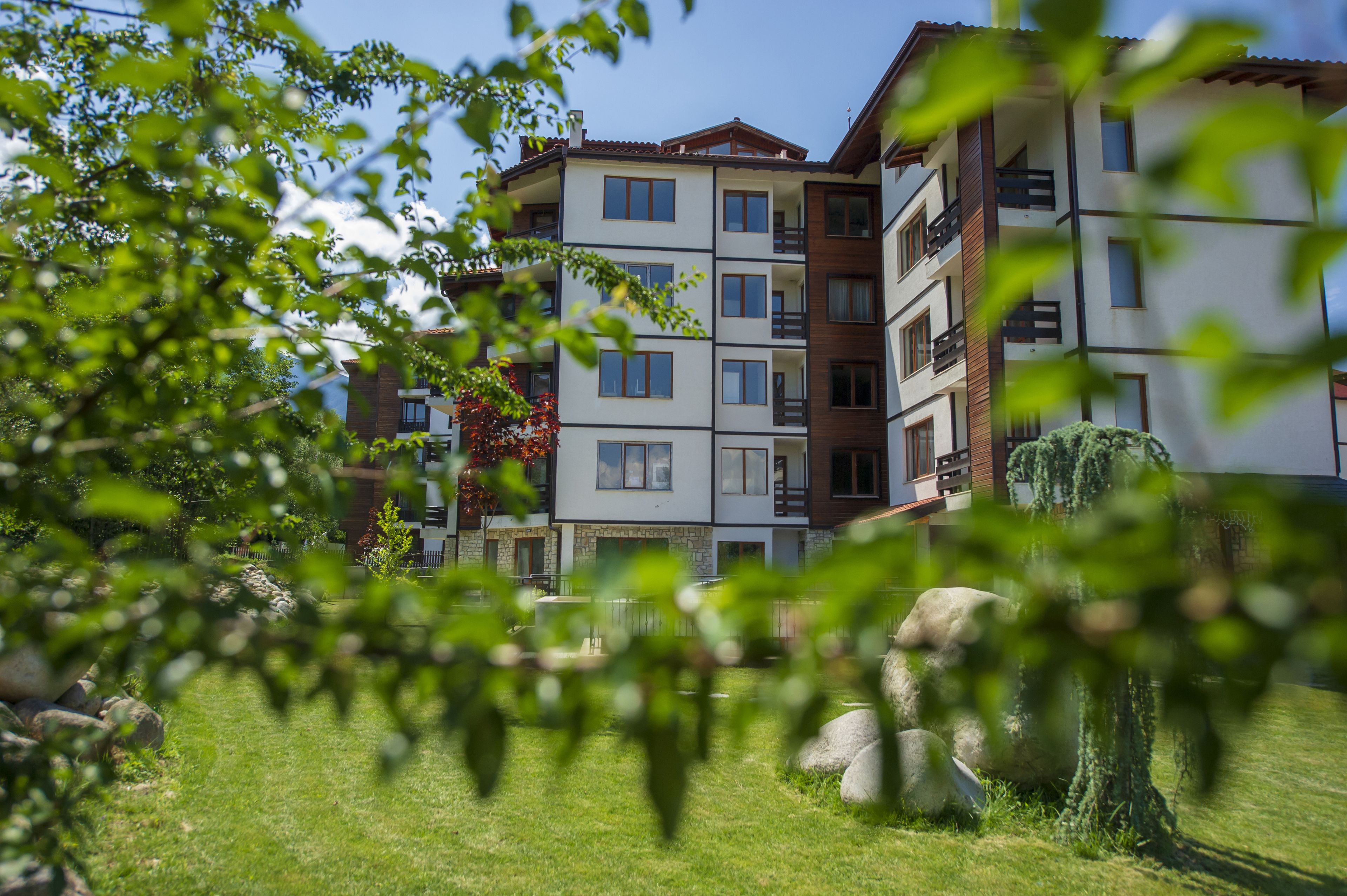 A multi-story residential building with balconies and a well-maintained lawn.