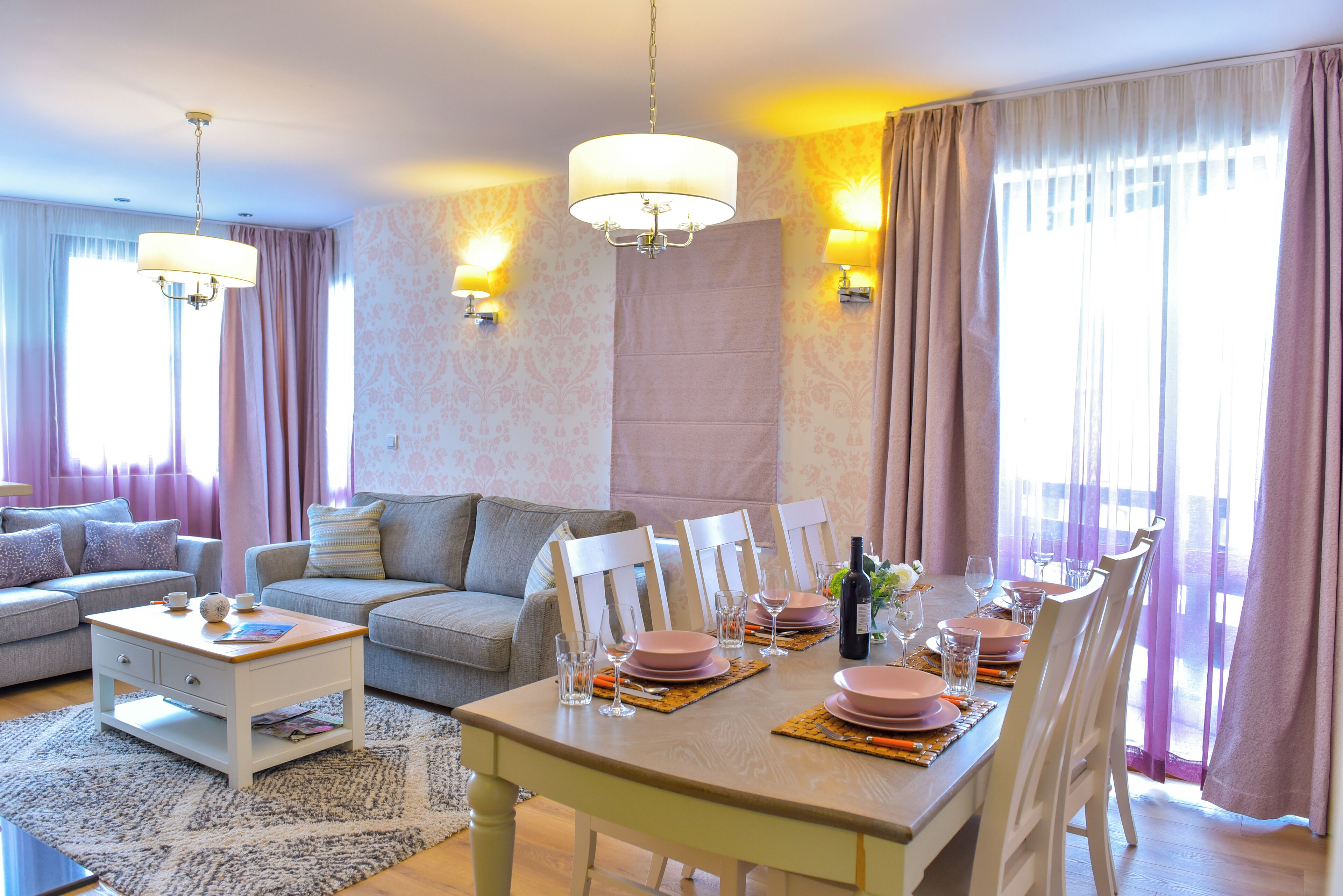 A dining area with a table set for four, surrounded by white chairs.