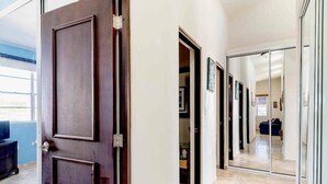Un couloir d’hôtel avec une porte en bois foncé, une porte en verre et un sol carrelé.