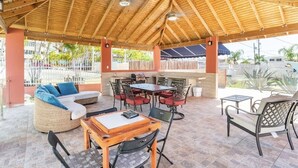 Une terrasse extérieure dotée d’un toit en bois, de meubles en osier et d’un espace bar.