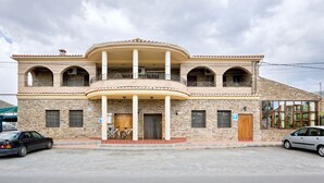 A two-story building with a central balcony, stone facade, and multiple windows.