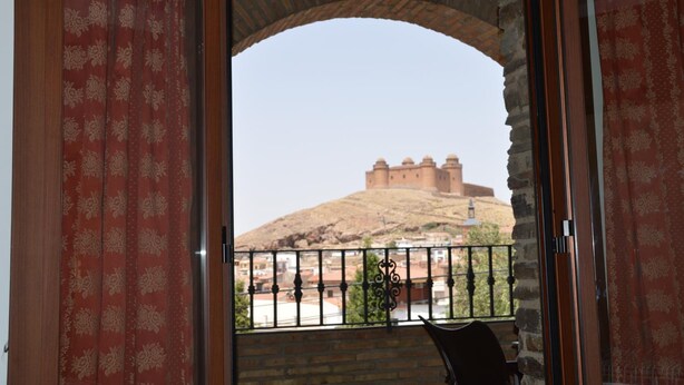 A balcony with a view of a hilltop fort.
