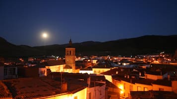 Una cittadina di notte con un'imponente torre dell'orologio, edifici illuminati e una chiara vista della luna.