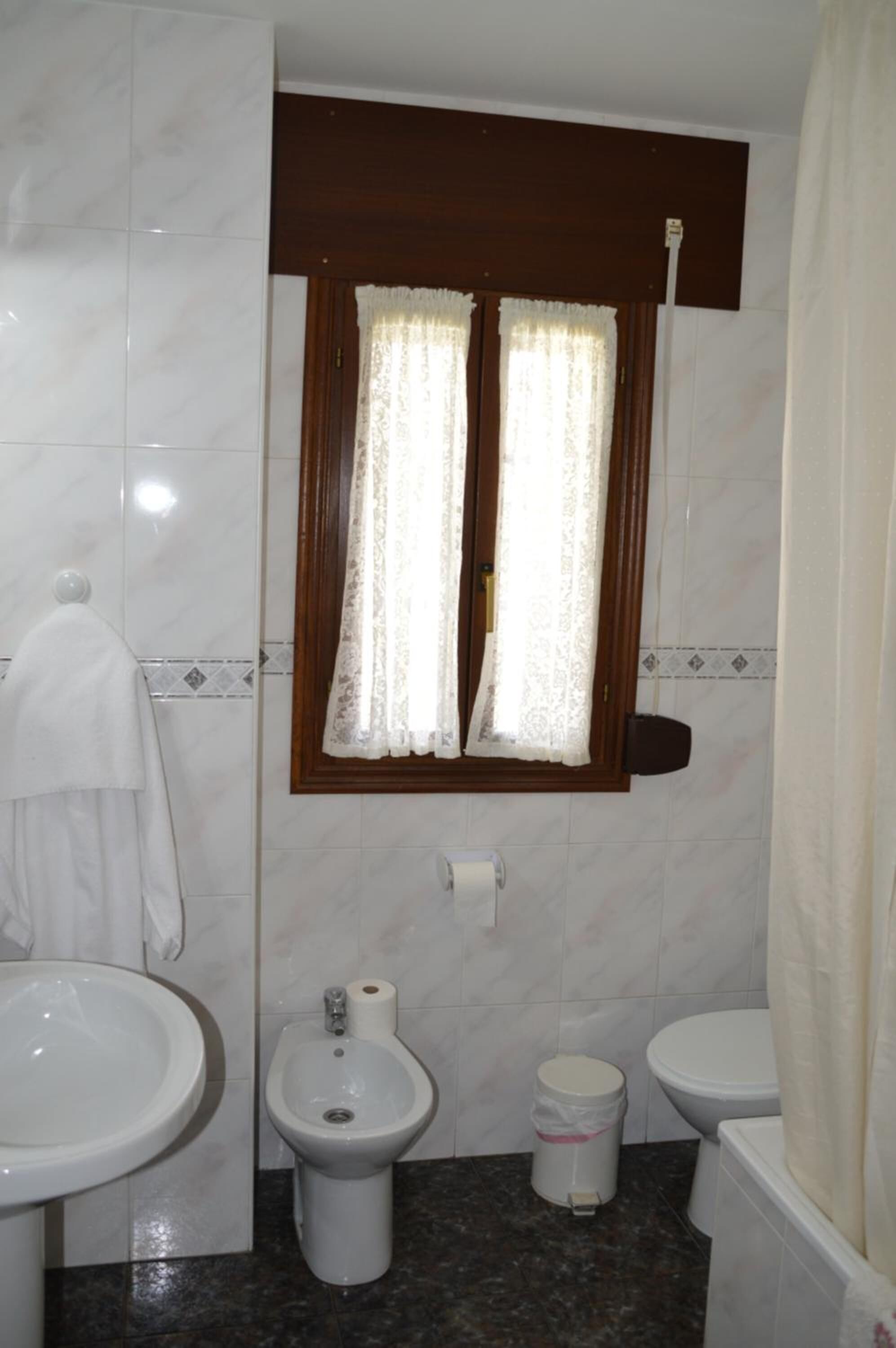 Bany amb rentatge, vàter, vàter i finestra amb cortines.