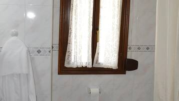 Bany amb rentatge, vàter, vàter i finestra amb cortines.