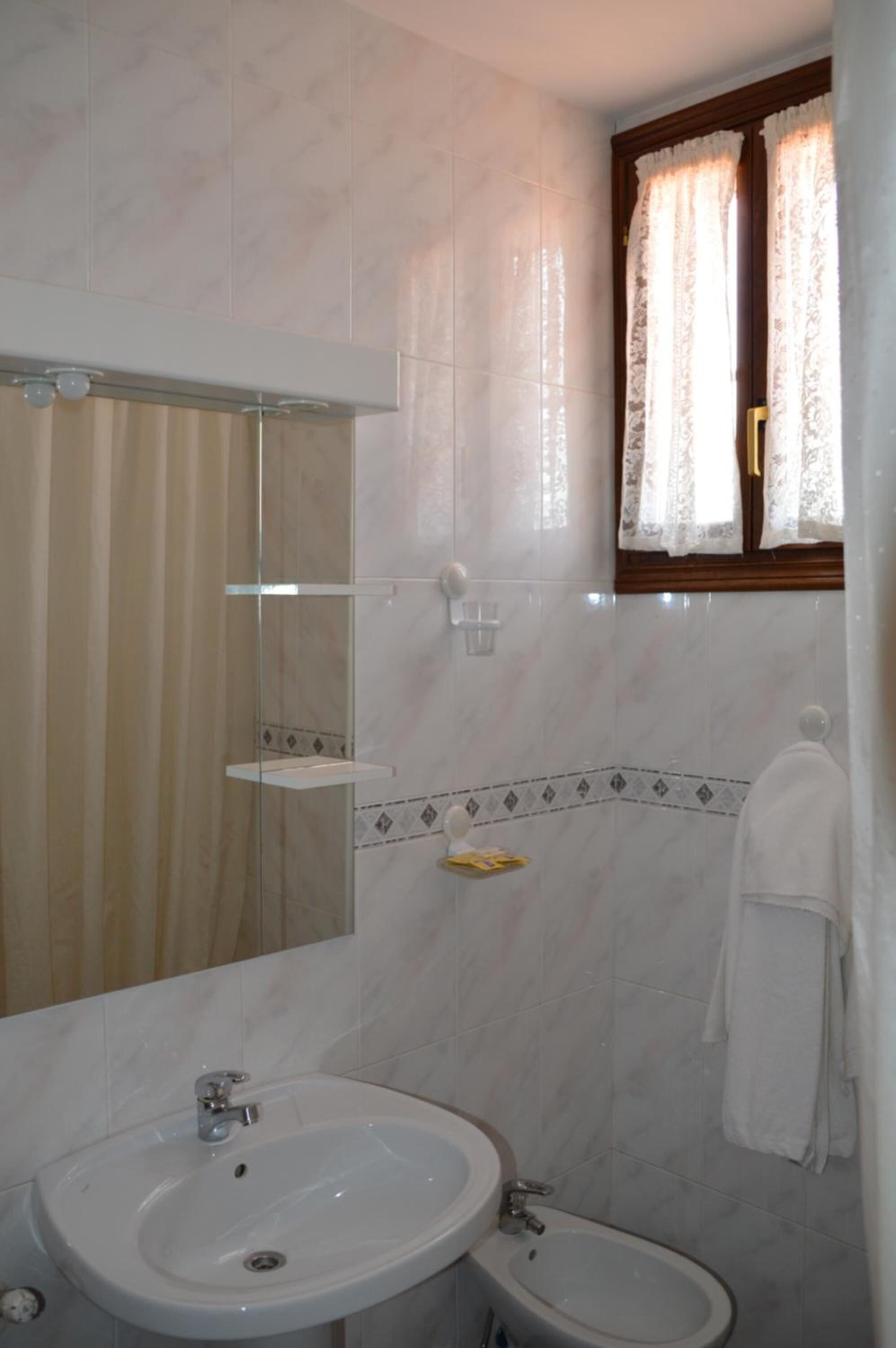Een badkamer met een wastafel, bidet en spiegel.