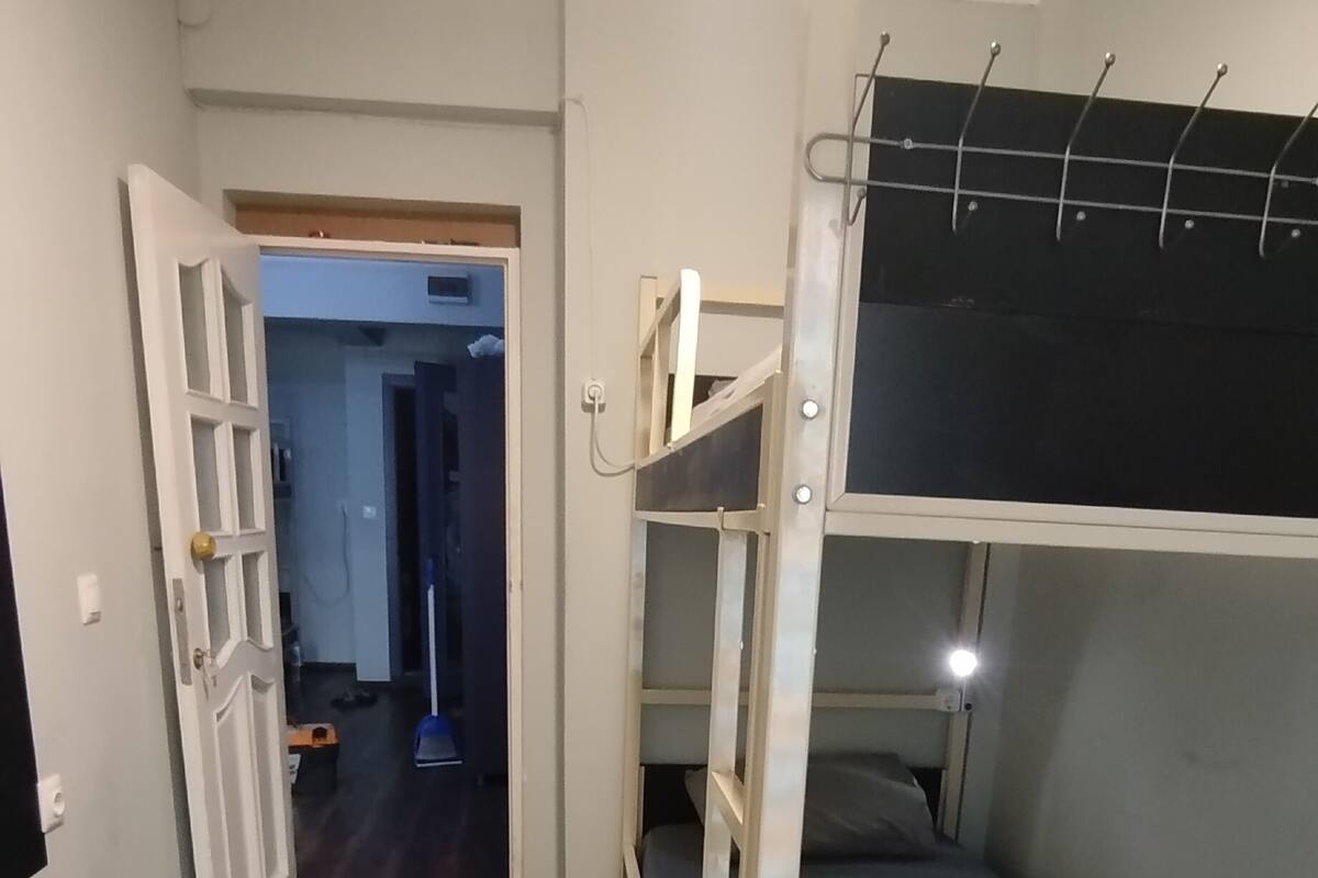 Een kamer met een stapelbed, een houten dressoir en een deur naar een andere kamer.