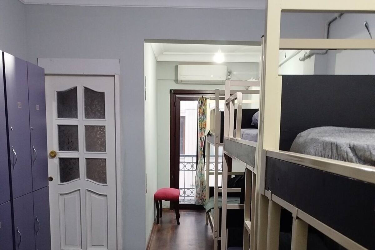 Een kamer met stapelbedden, een deur en een klein krukje.