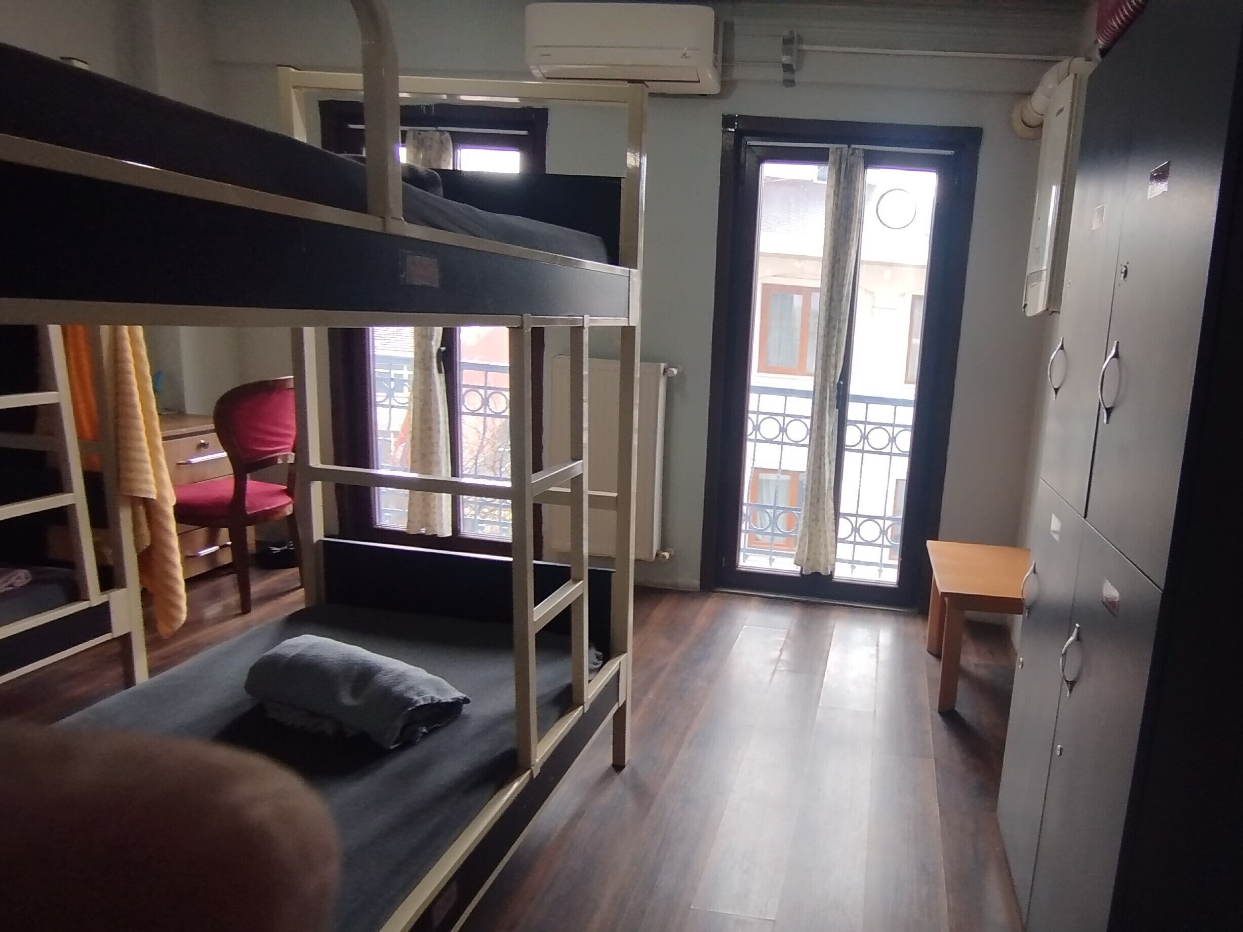 A dormitory room with bunk beds, a desk, a chair, and a wardrobe.