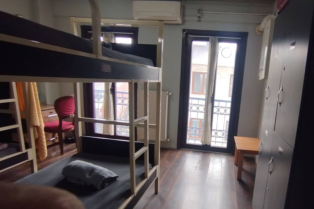 Een studentenkamer met stapelbedden, een bureau, een stoel en een kledingkast.