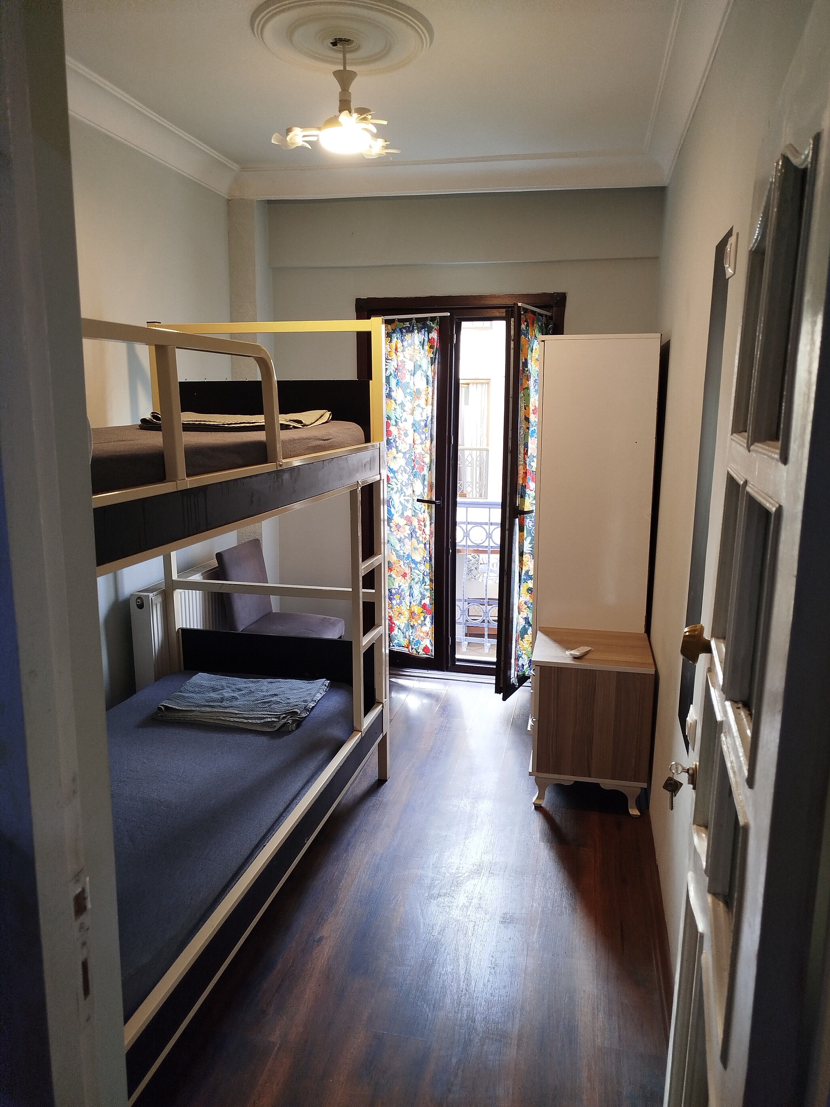A room with bunk beds, a wooden desk, a radiator, and a door with a key lock.