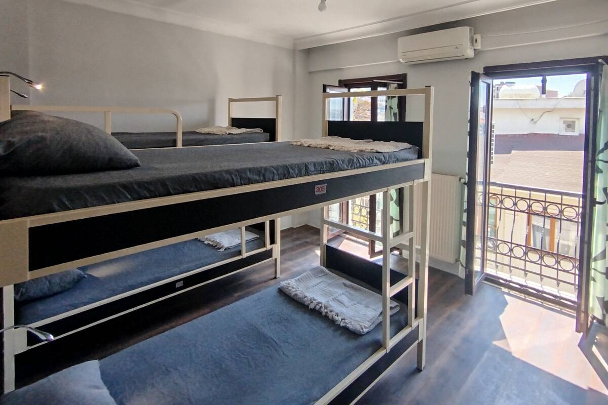 Een slaapzaal met stapelbedden, een raam en een airconditioning.