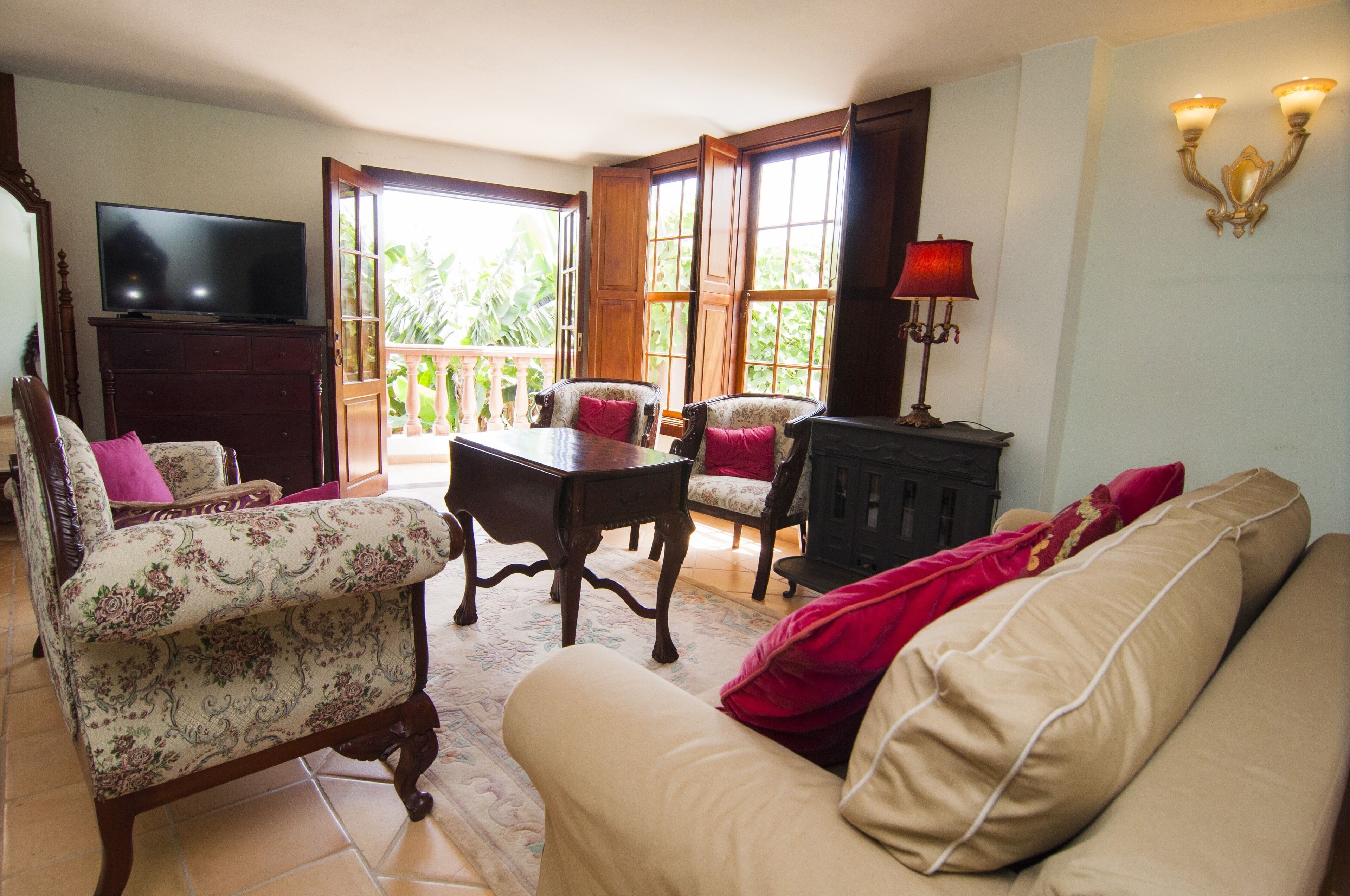 Una sala de estar con televisor, dos sillones, un sofá, una mesa y una lámpara.