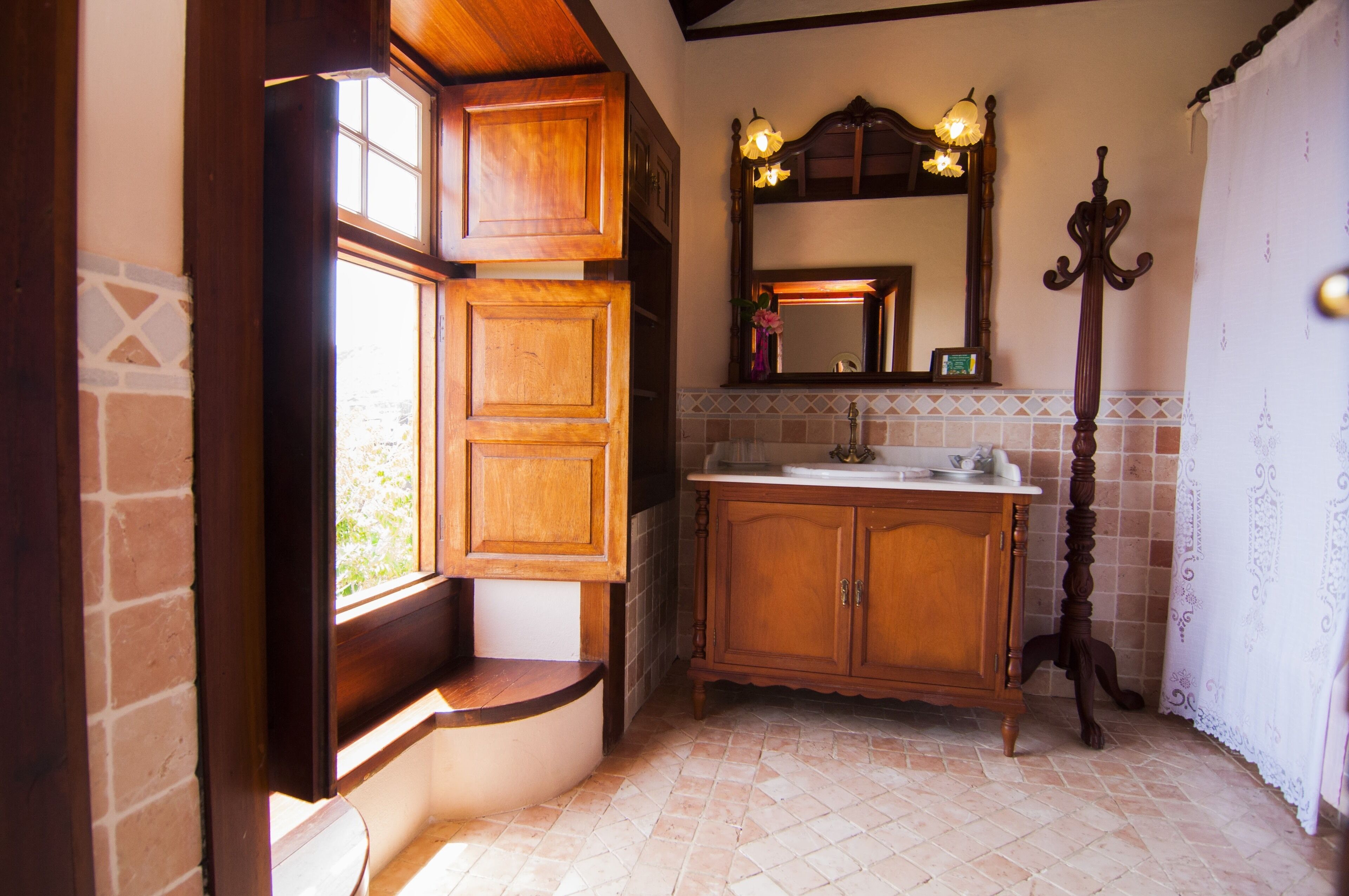 A bathroom with wooden cabinets, a sink, a mirror, and a window with a view.