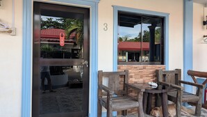 A building entrance with a glass door, a number '3' on the wall, and a wooden bench outside. - Aloha Seaside  Resort (San Juan)