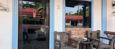 A building entrance with a glass door, a number '3' on the wall, and a wooden bench outside.
