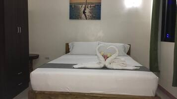 Una habitación de hotel con una cama, un cuadro de veleros en la pared y una decoración de toallas con forma de cisne.