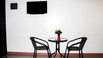 Una habitación con dos sillas, una mesa redonda pequeña y un televisor fijado a la pared.