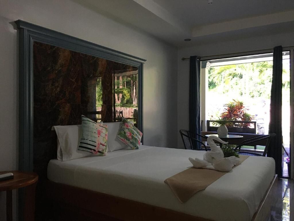 Een hotelkamer met een bed, een raam en uitzicht op groen.