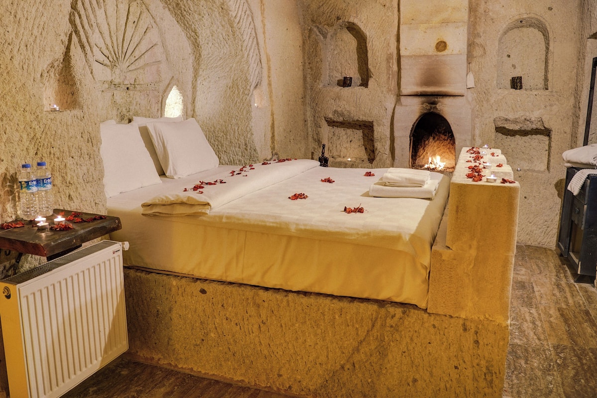 A stone-walled room with a bed, a fireplace, and a radiator.