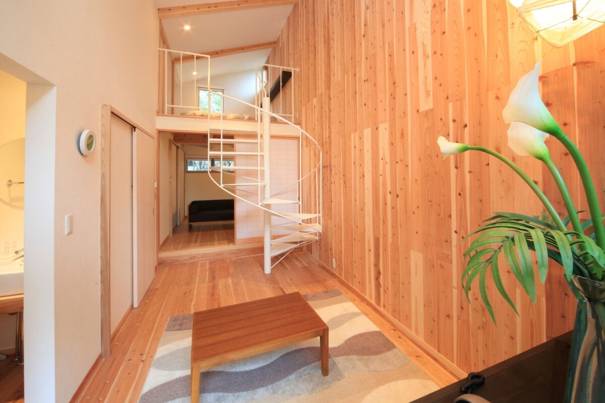 A wooden interior with a spiral staircase, a bench, and a plant.