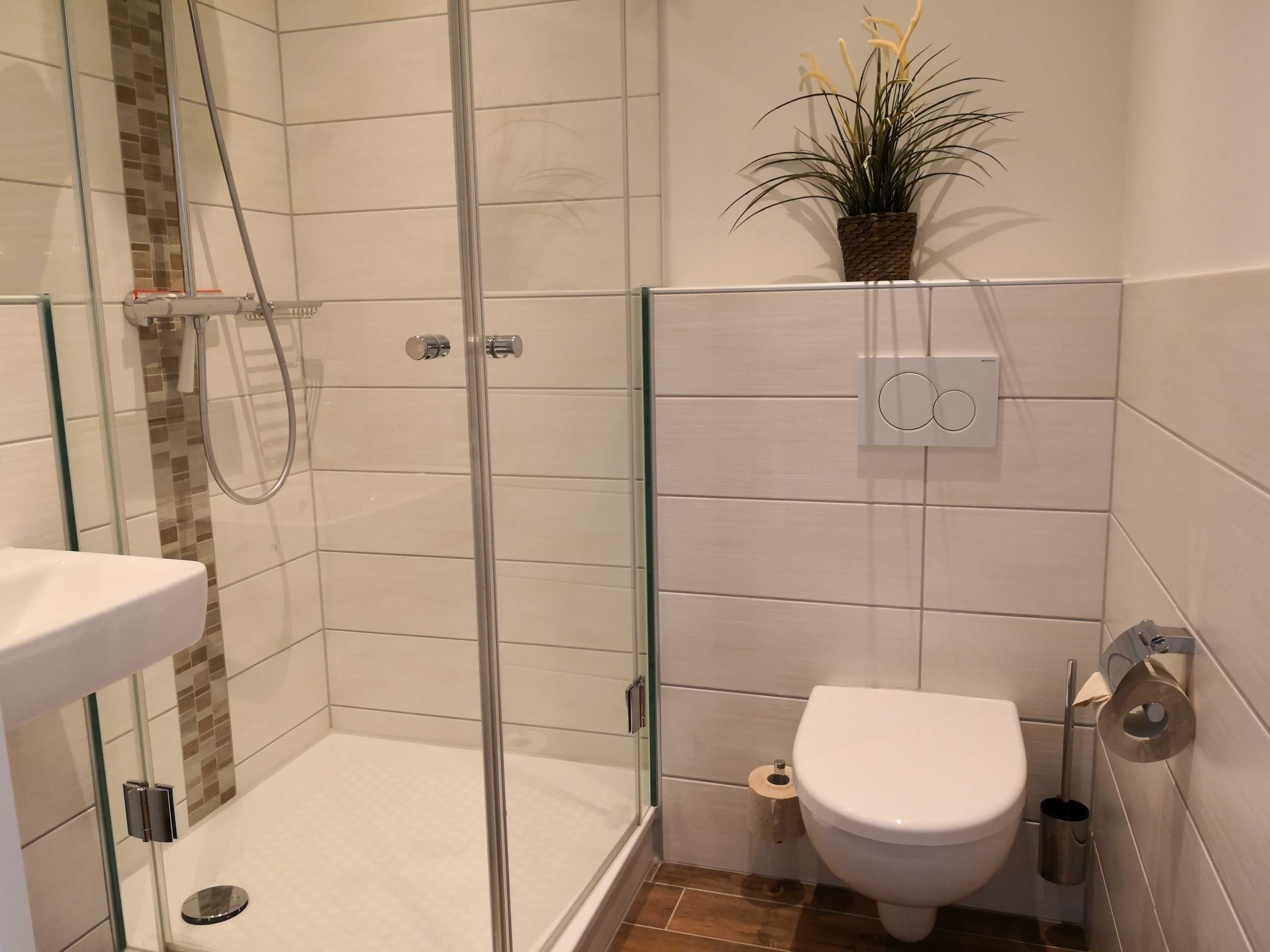 A bathroom with a glass-enclosed shower, a toilet, and a sink.