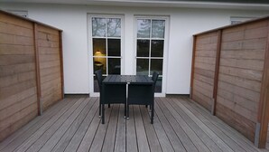 Un patio cubierto con una mesa y sillas, paredes de madera y una ventana con una lámpara en el interior.