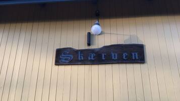 A wooden sign with the name 'Skerven' mounted on a building with vertical siding.