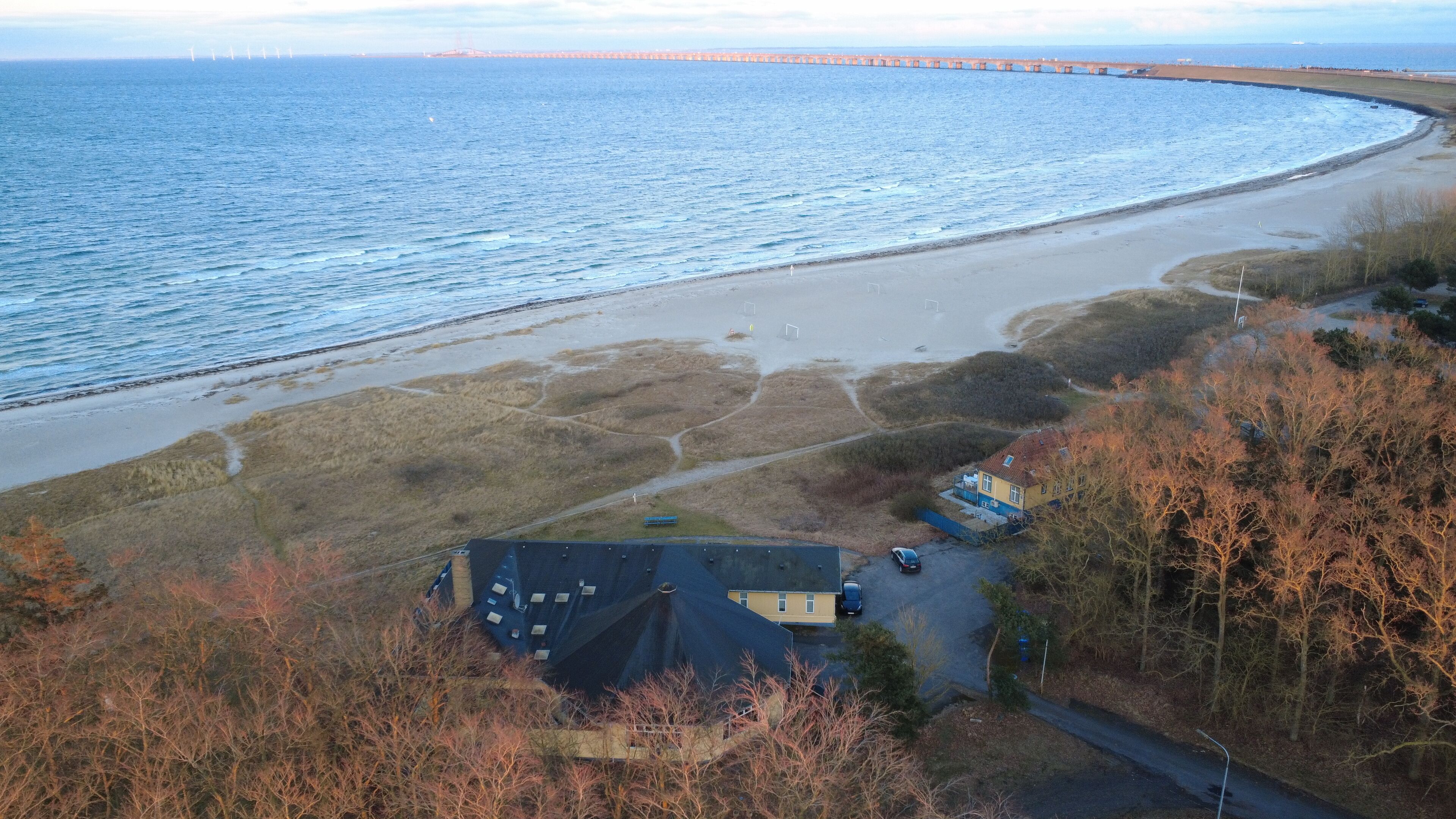 A coastal view with a beach, a house, and a road.