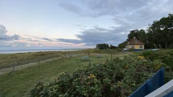 A coastal landscape with a house, grassy areas, and a pier extending into the water.