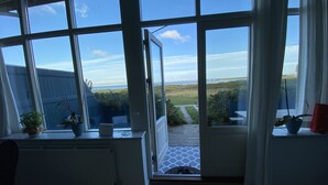 A room with large windows offering a view of a grassy area and a bridge. - Skaerven Beachfront Condos and Cottage (Nyborg)