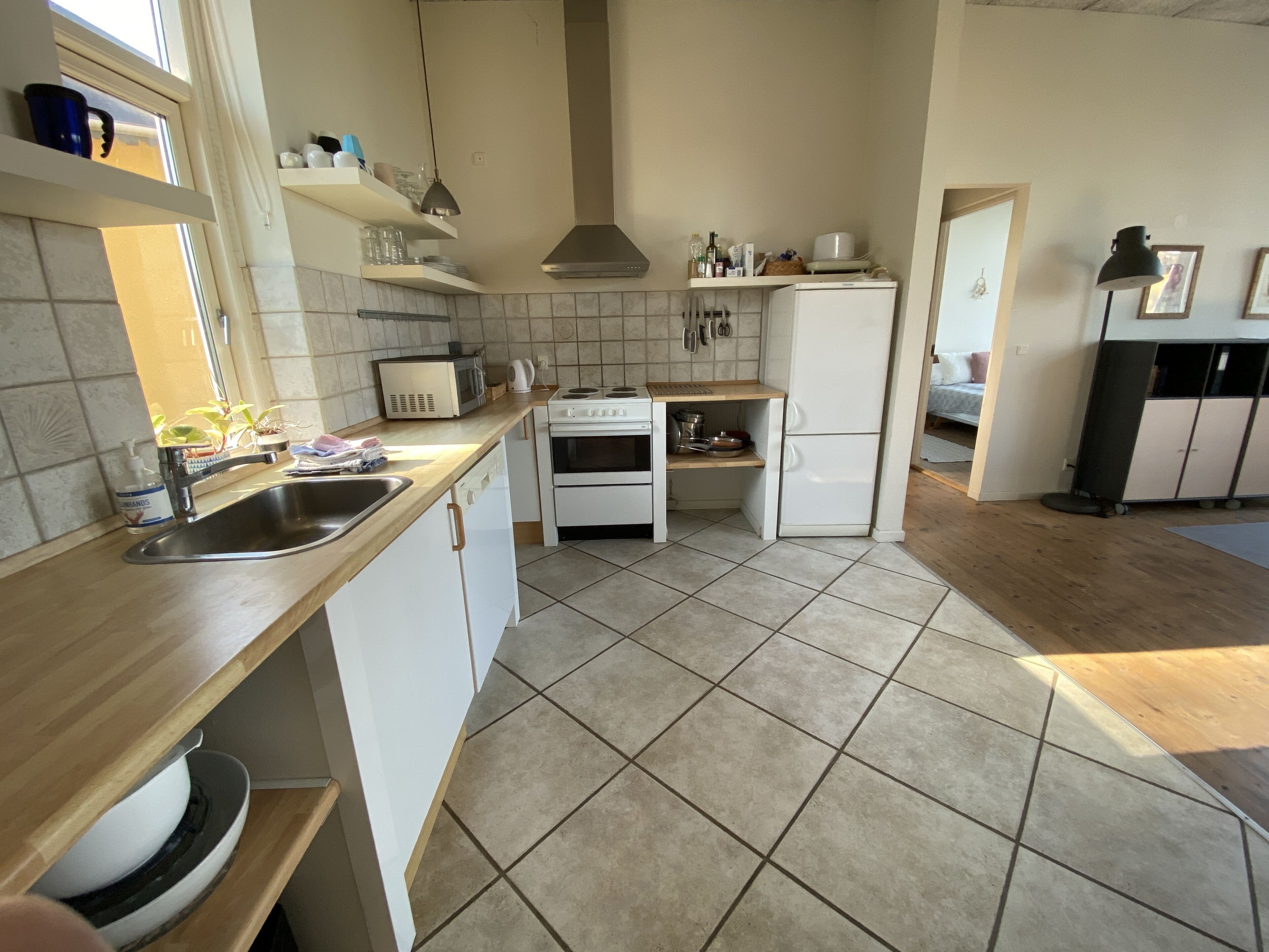 Een keuken met witte kastjes, een fornuis, een spoelbak en een koelkast.