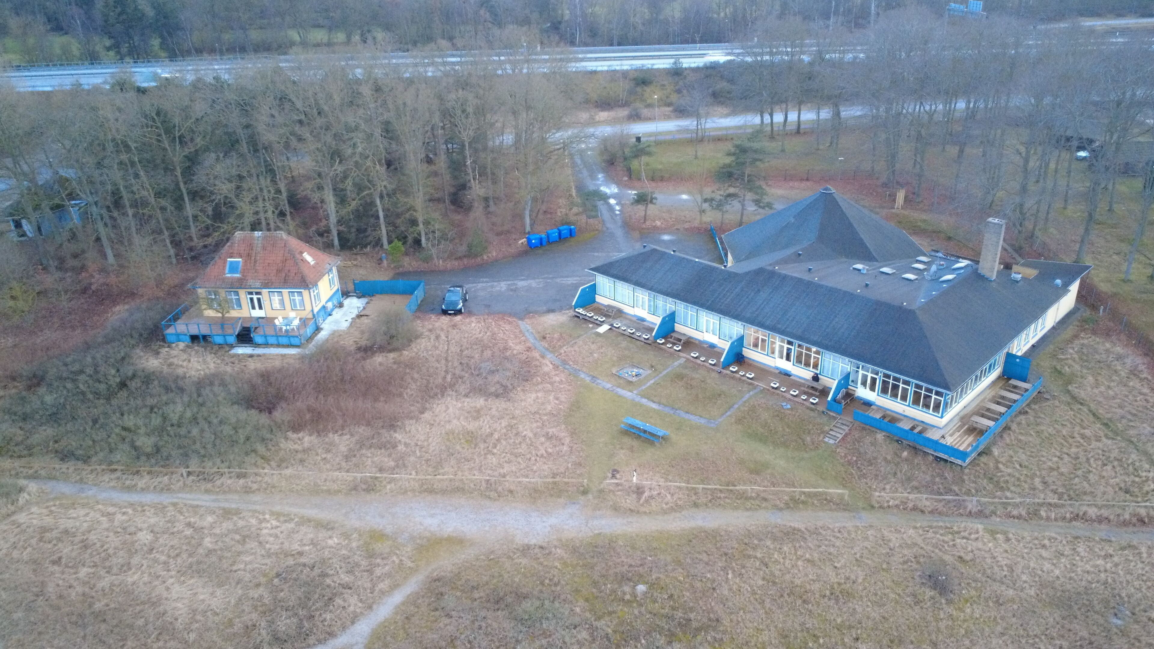 An aerial view of a property with a large house, a smaller attached structure, and a garage.
