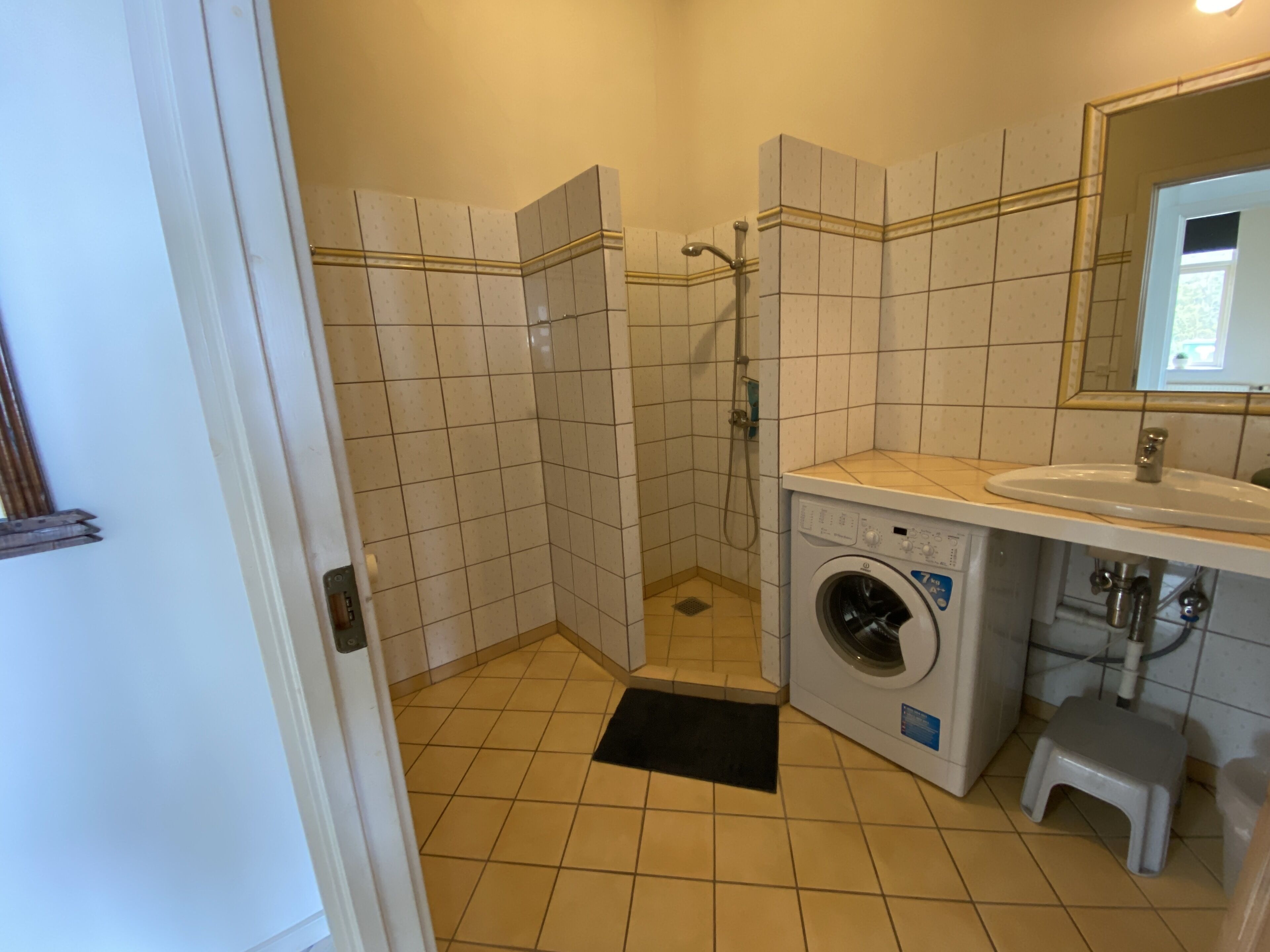 Un baño con lavadora, lavamanos y ducha.