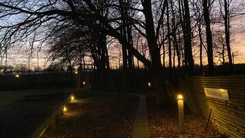 A pathway lined with trees and illuminated by ground lights, leading to a building with a 'Restaurant' sign.