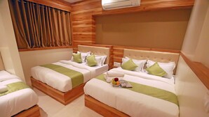 Ein Hotelzimmer mit zwei Betten, jeweils mit einem hölzernen Kopfteil, weißer Bettwäsche und grünen Akzenten.