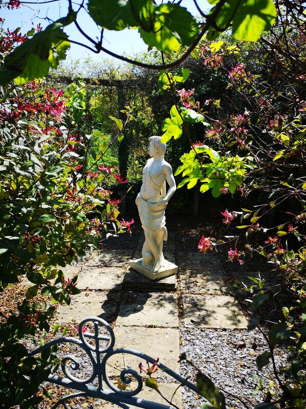 A statue in a garden with a stone pathway and metal fence. - Ael Y Bryn Bed and Breakfast (Crymych)