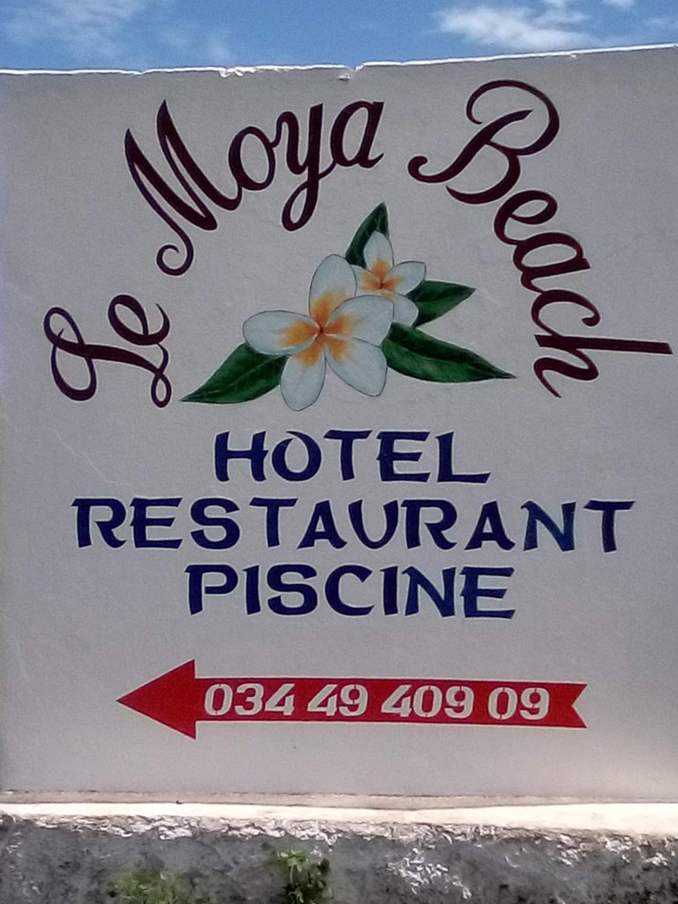 Señal para el restaurante, piscina y hotel Le Moya Beach, con un número de contacto.