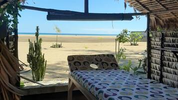 A beach hut with a bed and a view of the beach.