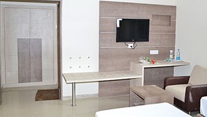 A modern living room with a flat-screen TV mounted on a wall, a small table, a sofa, and a door.